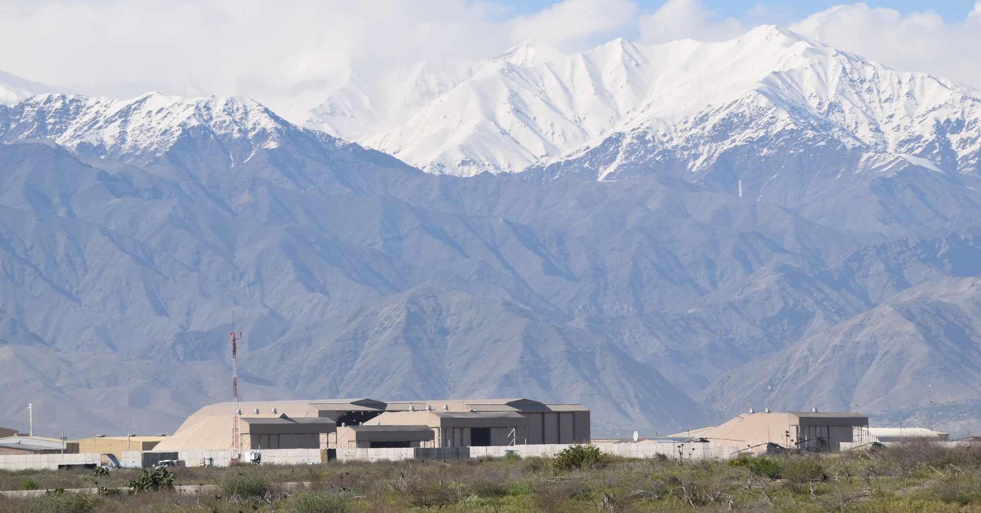 Image of Bagram, Afghanistan. The air base is visible in the foreground, with the Hindu Kush mountain range in the background.
