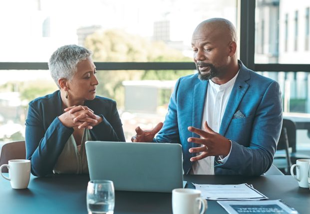 Man and woman business executives working together in an office sitting together reviewing computer screen