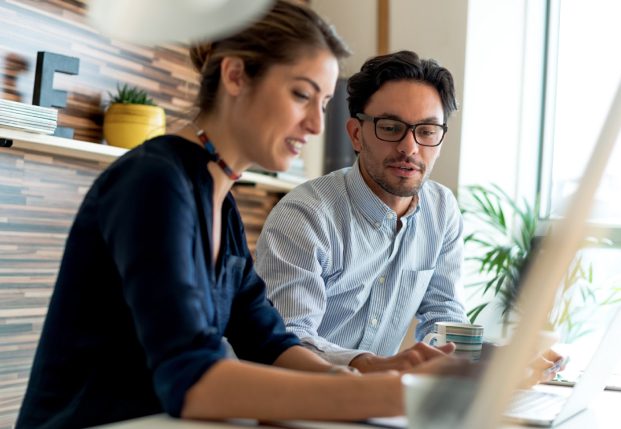 Two business colleagues working together in the office review information on a computer.